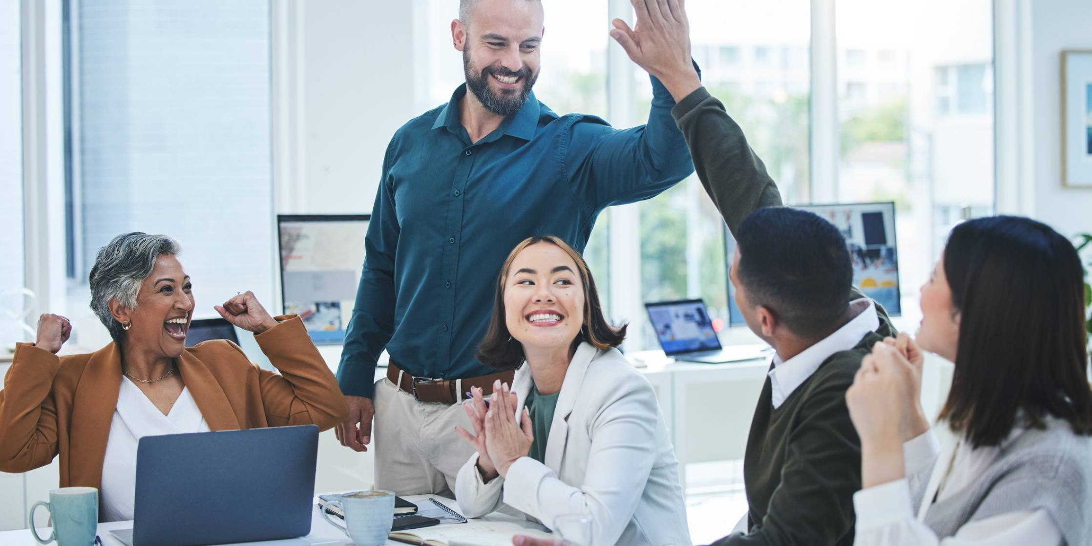 Group of people in a modern office setting with one person giving a high-five.