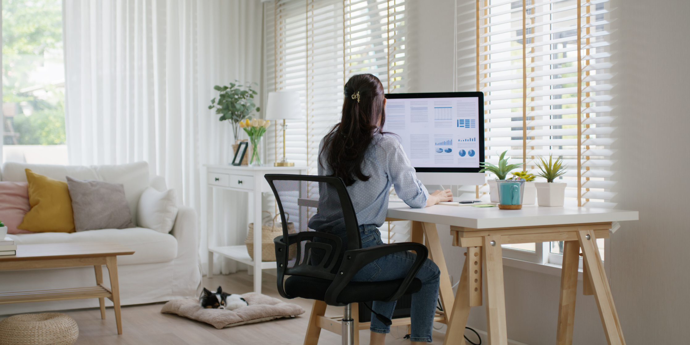 Person working on a computer at a desk in a bright, modern living room.
