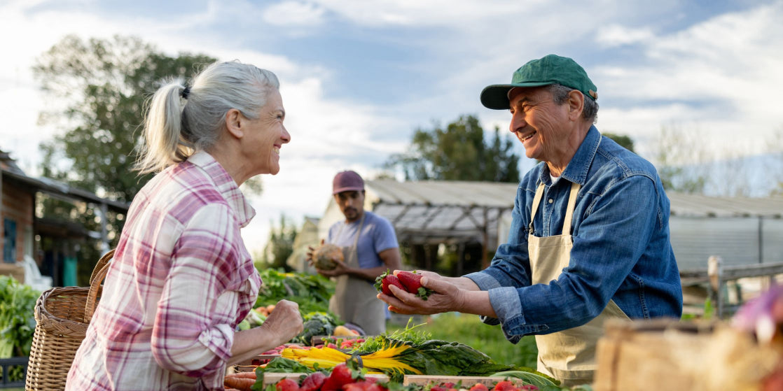 Happy Latin American farmer selling organic strawberries to a client at a Farmer's Market