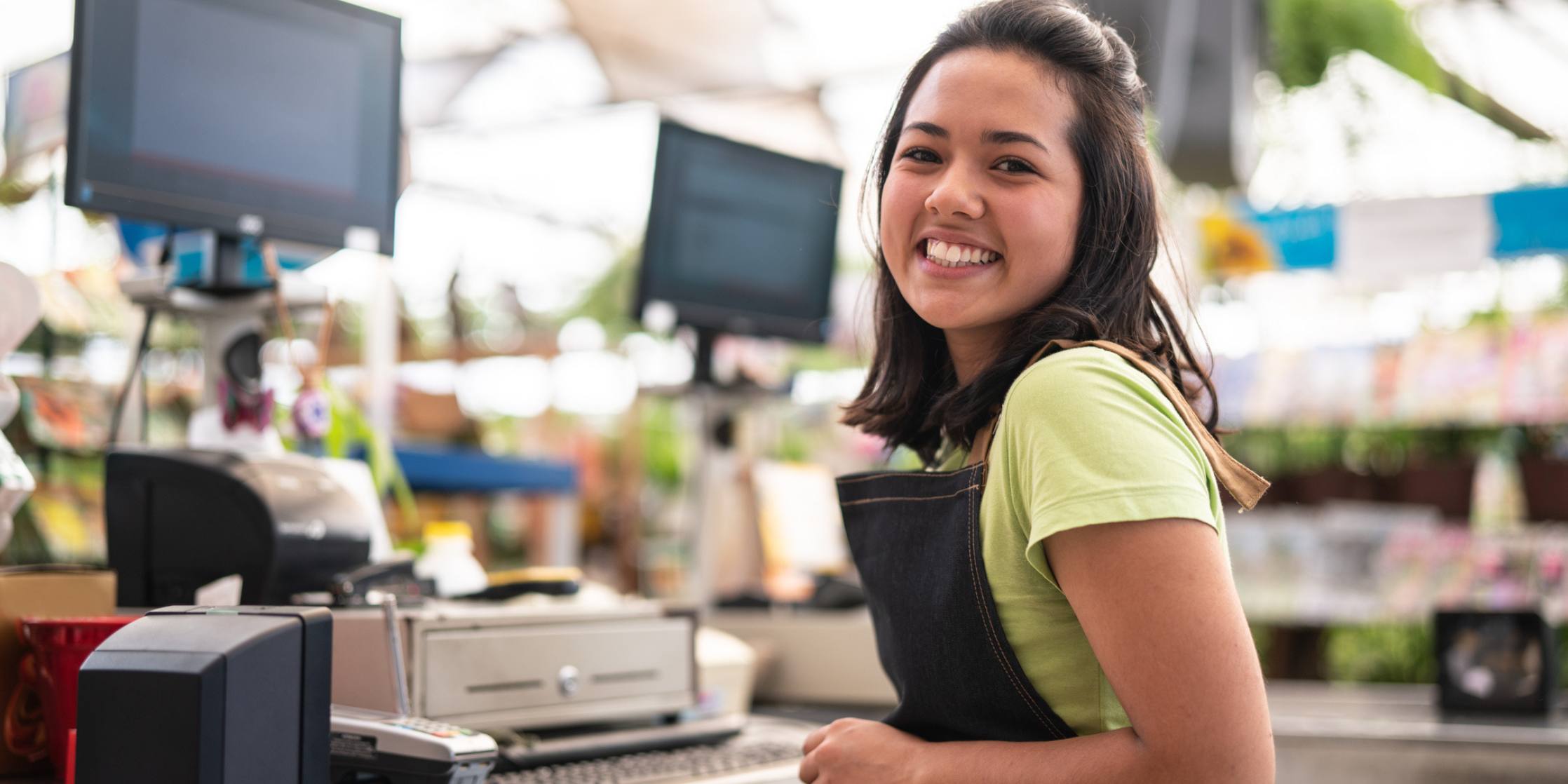 Portrait of confident owner leaning on checkout counter at flower shop - stock photo
