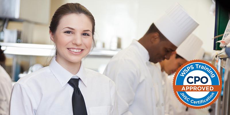Image of a female chef standing in kitchen with other chefs working in background