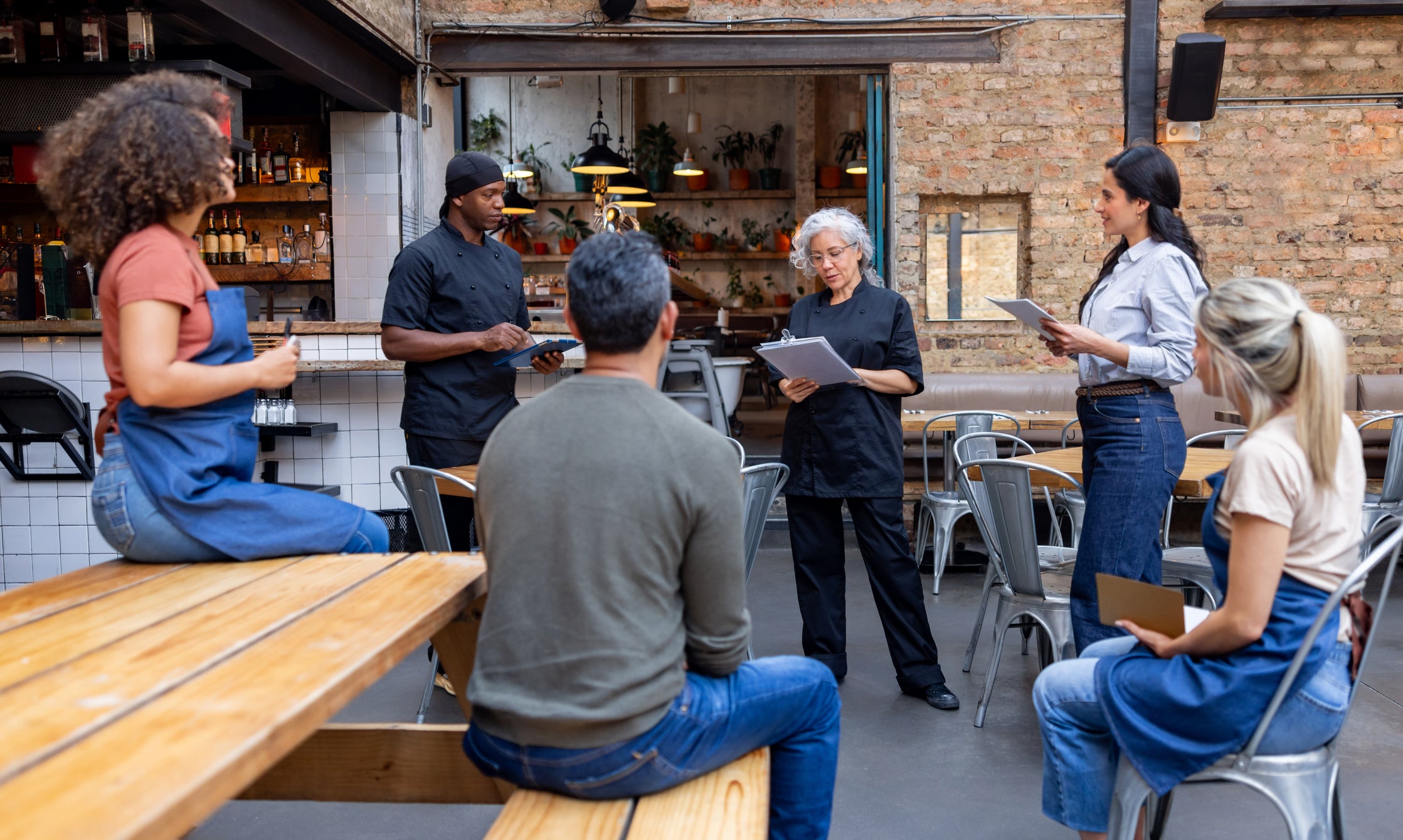 Group of people in a casual dining setting with one person holding a tablet.