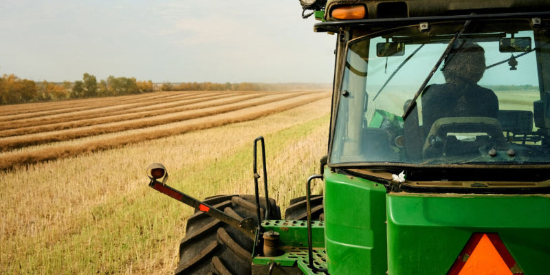 Rear view of farmer driving tractor on agricultural farm field