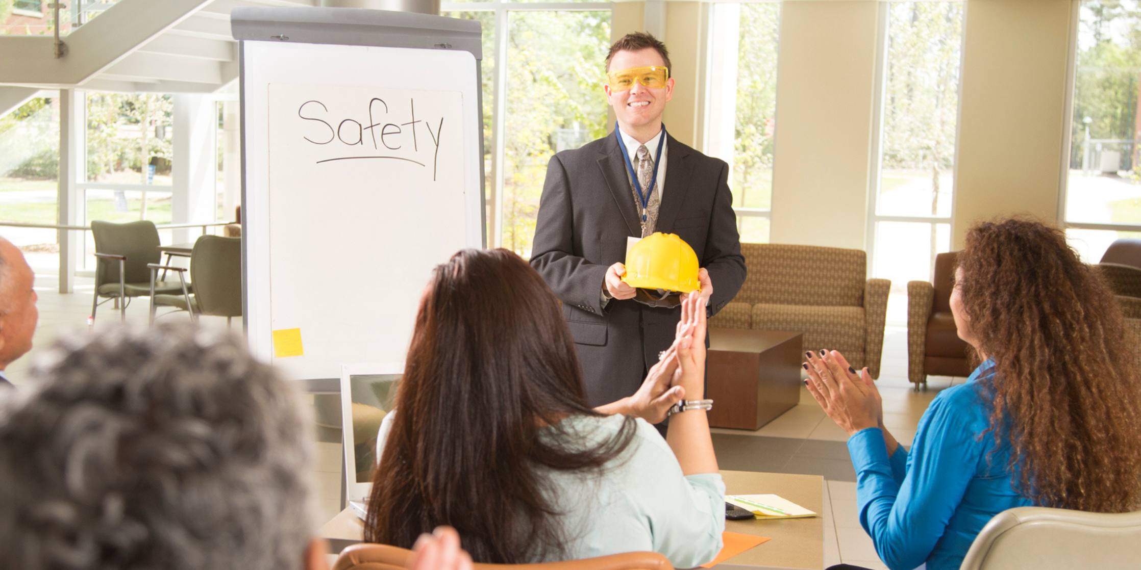 Person holding a yellow object in front of a 'Safety' sign during a training session.