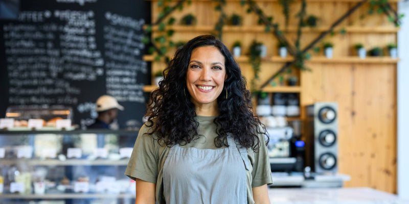 Woman standing in a coffee shop wearing an apron