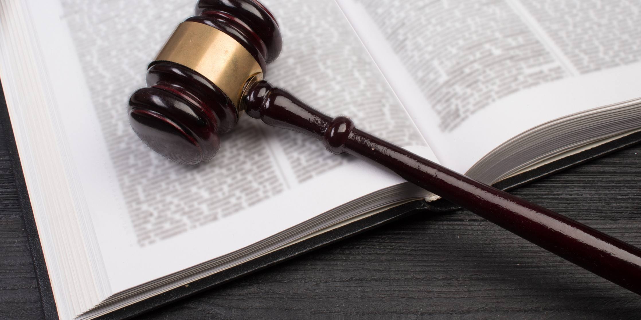 Wooden gavel on an open book, symbolizing law and justice.