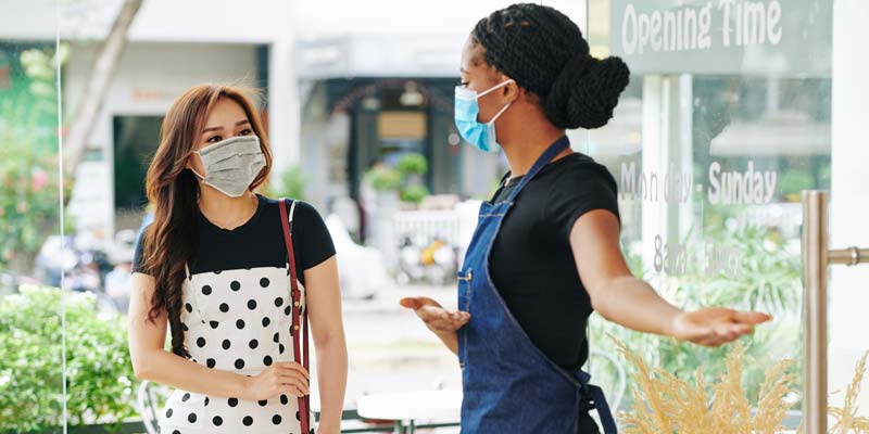 Image of a woman greeting a customer at store front 