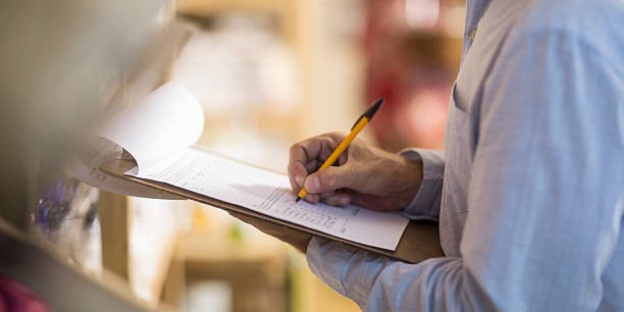 person filling out accident report on clipboard with pen
